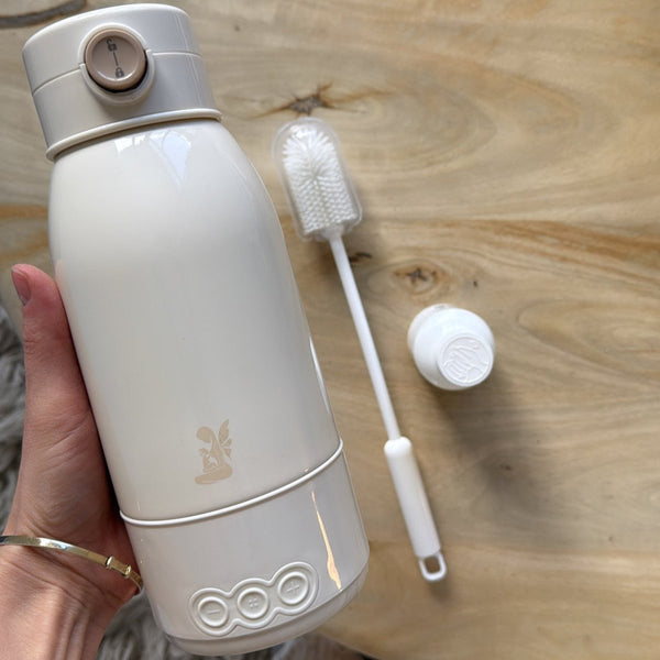 White water bottle with a straw and cleaning brush on a wooden surface